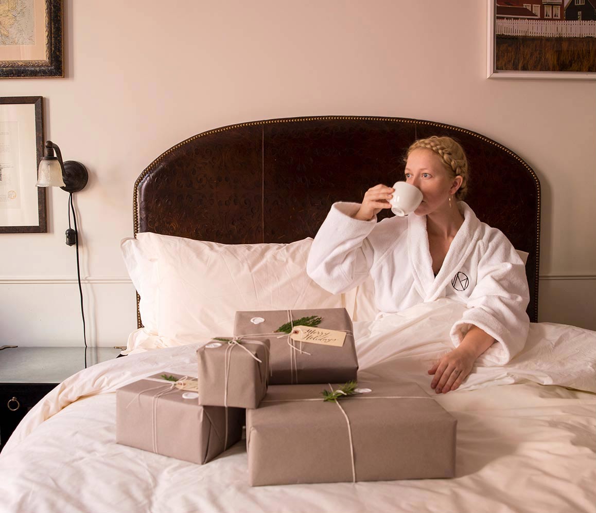 Woman in hotel bed with presents drinking tea image